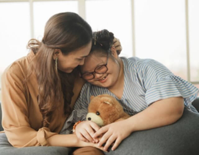 Mom hugging adult child with Down Syndrome